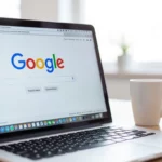 Egy laptop látható, amelyen a Google keresőoldala nyílt meg, egy fehér bögre mellett. A kép a keresőoptimalizálás és a hosszú farok kulcsszavak fontosságát hangsúlyozza.